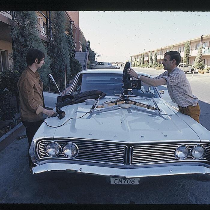 Two people affixing a camera to a car